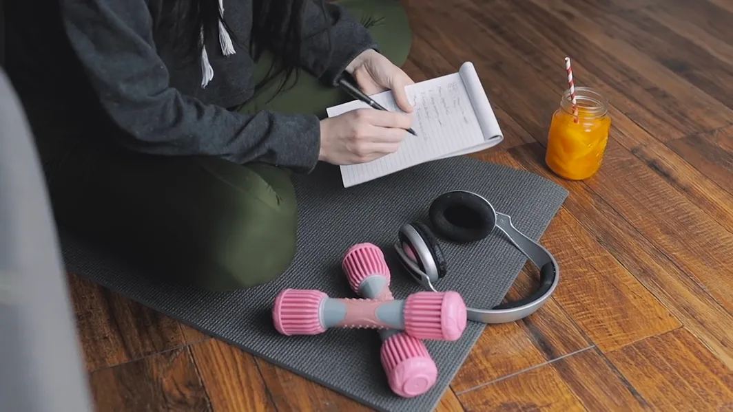 Person journaling with fitness equipment